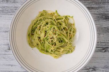 Yeşil pesto soslu spagetti, yabani sarımsak, zeytinyağı ve çam fıstığı tabakta, yakın plan, üst manzara