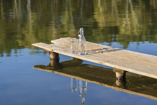 Szkło Butelka Wodą Pitną Drewnianym Pomoście Rano Pobliżu Jeziora Lasu — Zdjęcie stockowe