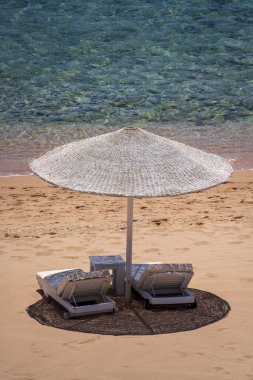 Mısır, Afrika 'daki Kızıldeniz kıyısındaki tropikal tatil beldesinde plaj sandalyeleri ve beyaz saman şemsiyeli lüks kumsal. Karantina sırasında boş plajlar