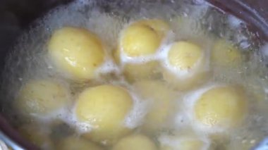 Tencerede sarı çiğ patatesle kaynayan suyun yakın görüntüsü. Genç patates kaynar suda kaynatılır.