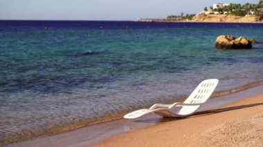 Mısır 'ın Sharm El Sheikh kentindeki tropikal bir plajda deniz suyunun yanında beyaz plastik güneş uzanır. Seyahat ve doğa kavramı