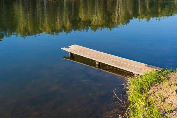 Tahta iskele ve Ukrayna 'da sakin bir göl üzerindeki bahar ormanı. Doğa ve seyahat kavramı. Güzel ve renkli bir sahne.