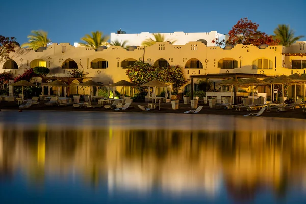 Gebäude Liegestühle Und Sonnenschirme Spiegeln Sich Nachts Ruhigen Meerwasser Strand — Stockfoto