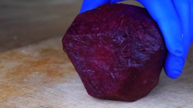 Kırmızı pancar kökünü keskin şef bıçağıyla kesmek, makro shot, pişirme işlemi, yemek için malzemeleri hazırlamak. Haşlanmış pancara yakın, sağlıklı bir yaşam tarzı.