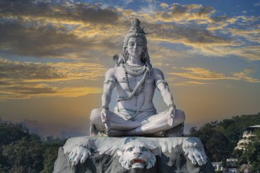 Hindu tanrısı Shiva 'nın gökyüzüne karşı meditasyon heykeli ve Hindistan' ın Rishikesh köyündeki Ganj Nehri üzerindeki bulutlar.