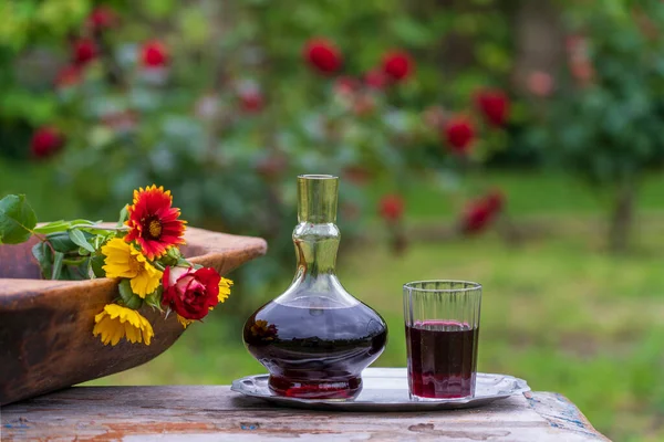 木製のテーブルの上の夏の庭の背景に赤ワインとガラスのデカンタとガラス クローズアップ — ストック写真