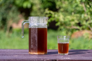 Bahçedeki cam sürahide mayalı ve malt aromalı ev yapımı ekmek kasesi, yakın çekim. Yaz içkisini cam kavanozda ve cam bardağı bahçedeki ahşap masada tazeliyorum.