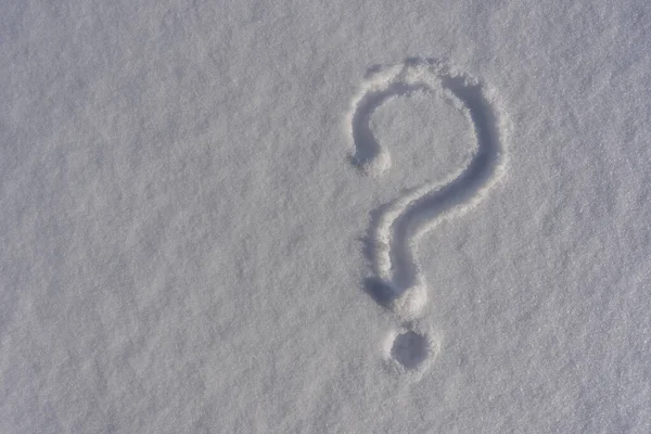 Question mark on a white fresh snow in winter, close up. Question mark on snow natural surface, copy space background