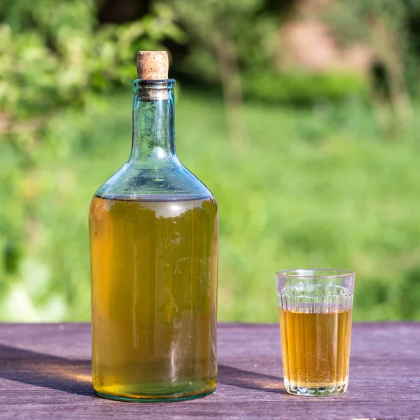Homemade wine in a big glass bottle on nature background in garden, close up