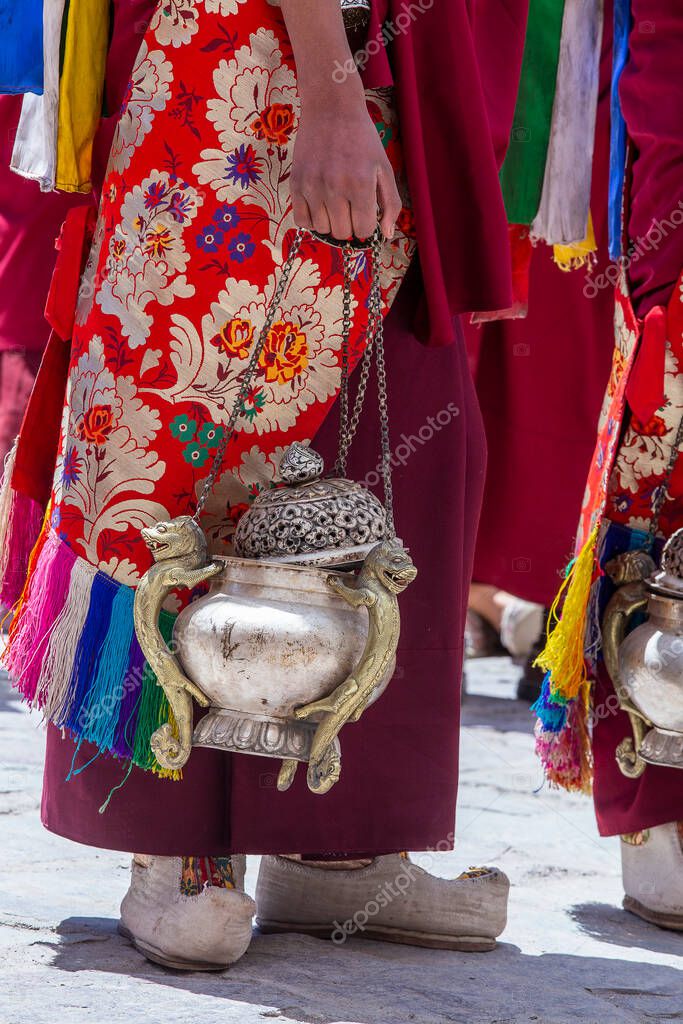 Tibetan monk holds a censer, a metal vessel for smoking incense, during