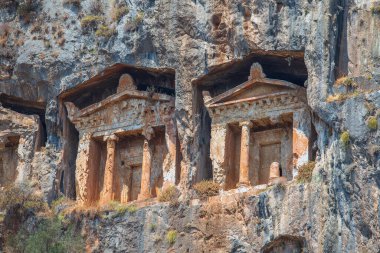 Antik Caunos kasabası Dalyan, Mugla, Türkiye 'nin ünlü Lycian Rock Mezarları. Türkiye 'nin antik mimari harikalarından biri olan Kaunos' taki kaya kesimli tapınak mezarları uçurumlara oyuldu.