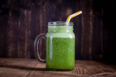 Avokado, muz, maydanoz ve bal cam kupa ahşap zemin, üzerine gelen taze yeşil smoothie kapatın. Sağlıklı beslenme kavramı