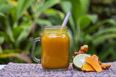 Zerdeçal, zencefil, limon ve ballı enerji içeceği cam bardak, doğa arka planı, kapat