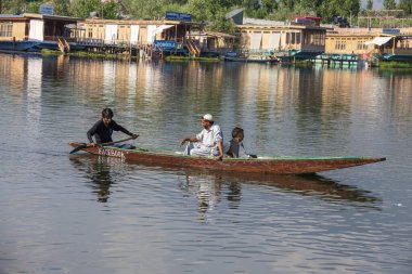 Srinagar, Hindistan - Temmuz 02, 2015: Dal Gölü 'nde yaşam tarzı, Hindistan' ın Srinagar, Jammu ve Kashmir eyaletlerinde küçük bir taşımacılık teknesi olan Shikara 'yı kullanıyor. Teknedeki Hintli adamlar