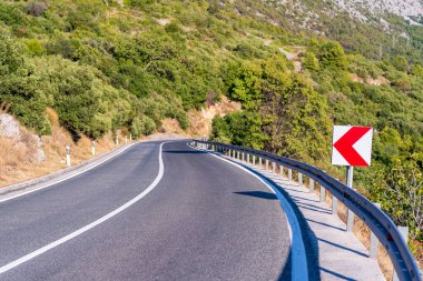 Yaz zamanı, Avrupa 'da dağ yolunda yol uyarı levhası bükün.