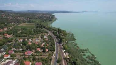 Balaton Gölü 'nün havadan görünüşü, su gölü boyunca arabalı yollar, evler, tarlalar ve Macaristan' daki bahçeler.