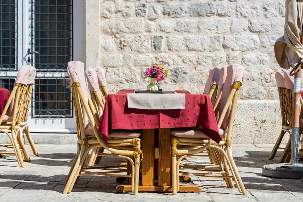Rattan chairs and table in a street restaurant in the old town of Kotor, Montenegro, Europe