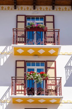 İtalya, Dolomitler 'de renkli çiçeklerle dolu taştan bir dağ evinin balkonunu kapatın.