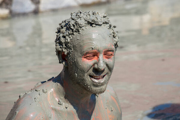 Mud treatment at the Dalyan, Turkey. Portrait happy man who takes a mud bath, close up