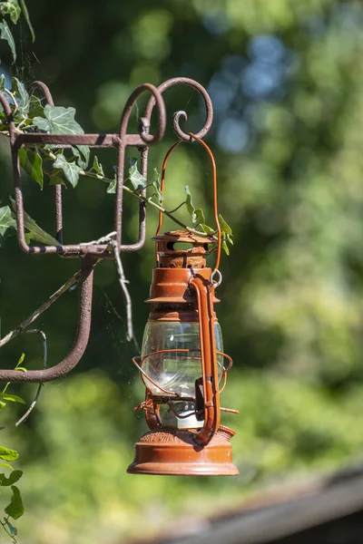 Een Enkele Oude Rode Kerosine Lantaarn Hangend Tegen Een Tuin — Stockfoto