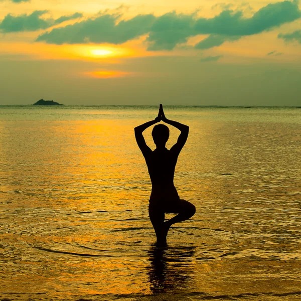 Yoga kvinnor silhouette, arbetar på poser vid solnedgången — Stockfoto