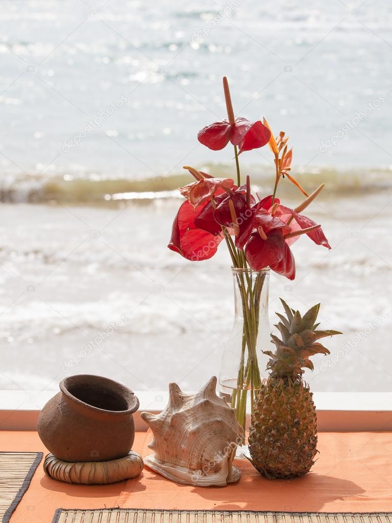 Pineapple, shell, flowers on a beach table
