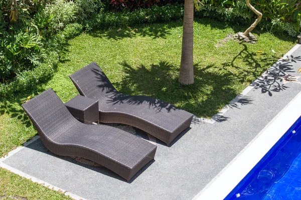 Two beach chairs next to a swimming pool in a tropical garden. Top view — Stock Photo, Image