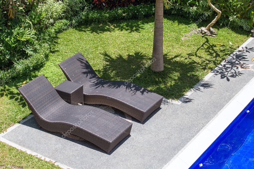 Two Beach Chairs Next To A Swimming Pool In Tropical Garden Top View Two Beach Chairs Next To A Swimming Pool In Tropical Garden Top View