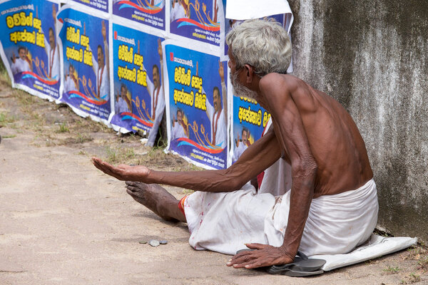Sri Lankan beggar waits for alms on a street next to the bus station