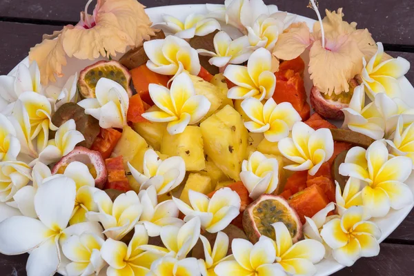 Efterrätt fruktsallad med ananas, papaya, passionsfrukt och vit frangipani blomma — Stockfoto