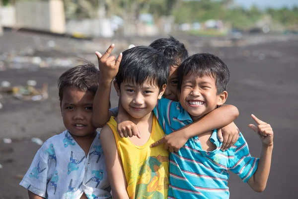 Niños pobres pero sanos no identificados agrupan retrato en la playa con arena volcánica cerca del volcán Mayon —  Fotos de Stock