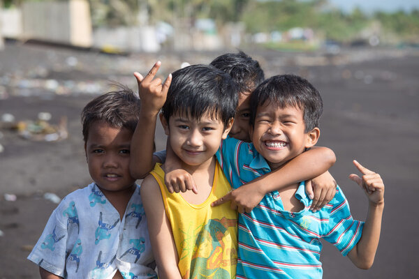 Unidentified poor but healthy children group portrait on the beach with volcanic sand near Mayon volcano