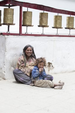 Indian poor woman with children begs for money from a passerby on the street in Leh, India clipart