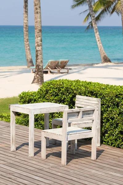 Beautiful sea, coconut palm tree, wooden table and chairs — Stock Photo, Image