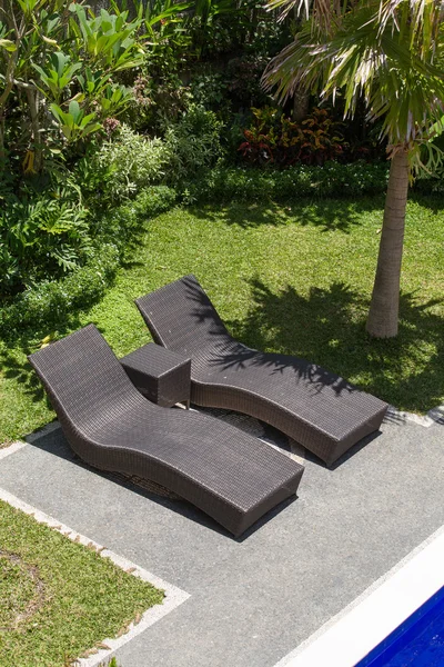 Quelques chaises longues au bord de la piscine dans un jardin tropical. Bali, Indonésie — Photo