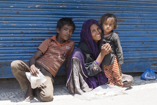 Indian poor woman with children begs for money from a passerby on the street in Srinagar, India