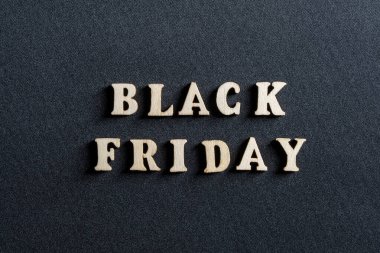 Siyah arka planda siyah Cuma yazılı ahşap harfler, yakın plan, üst manzara. Mağazalarda terfi ve satış zamanı.