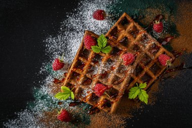 Kahvaltıda taze pişmiş Belçika waffle 'ı, kırmızı ahududu ve siyah tabakta reçel, yakın plan, üst manzara. Mutfak, yemek pişirme, fırın konsepti. Yemek tarifi geçmişi. Çilekli tatlı waffle