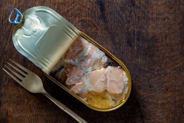 Somon balığı filetosunu kendi meyve suyu ve metal çatalıyla ahşap masa arka planında aç, kapat, üst manzara