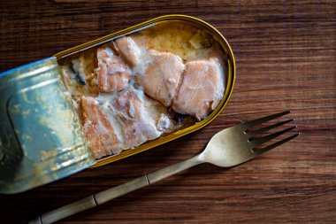 Somon balığı filetosunu kendi meyve suyu ve metal çatalıyla ahşap masa arka planında aç, kapat, üst manzara