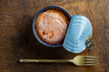 Somon balığı filetosunu kendi meyve suyu ve metal çatalıyla ahşap masa arka planında aç, kapat, üst manzara