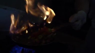 Şef, sebzeleri kızartıp tavaya atıyor. Türkiye 'deki sokak kafesinde sebzeli kızartma tavalarının büyük bir alevle kavruluşunun yavaş çekim görüntüsü. Mutfakta kızarmış sebze pişireceğim.