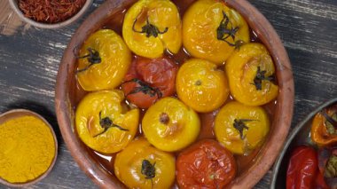 Fırınlanmış kırmızı ve sarı domates ve dolmalık biber. Ahşap bir masada fırın kabında domates ve dolma biber. Sağlıklı ve lezzetli bir vejetaryen yemeği. Kapat, üst görünüm, döndür