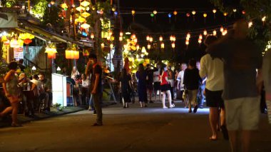 Hoi An, Vietnam - 15 Mart 2020: Avrupalı turistler eski Hoi An şehrinin merkezindeki restoranların yanında nehir boyunca yürüyorlar.