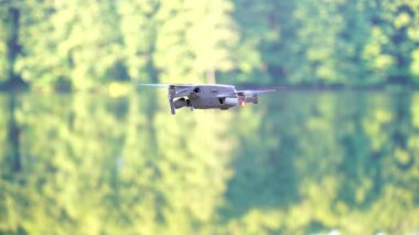 Kiev, Ukrayna - 01 Ekim 2021: DJI Maviç Air 2S İHA 'sı, bir önceki Maviç modeline göre büyük bir güncelleme yaparak, arka planda asılı duruyor. DJI Mavic Air 2S İHA 'sı orman gölünde uçuyor.