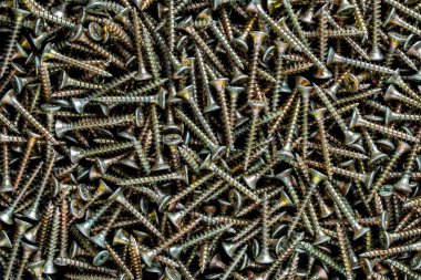Yüksek çözünürlüklü yakın plan bir fotoğraf birçok parlak altın evrensel kendi kendine tıkırdayan vidalar karşı batmış başlarla, büyük dağınık bir yığın bir araya. Donanım, inşaat, onarım ve DIY proje kavramları için mükemmel