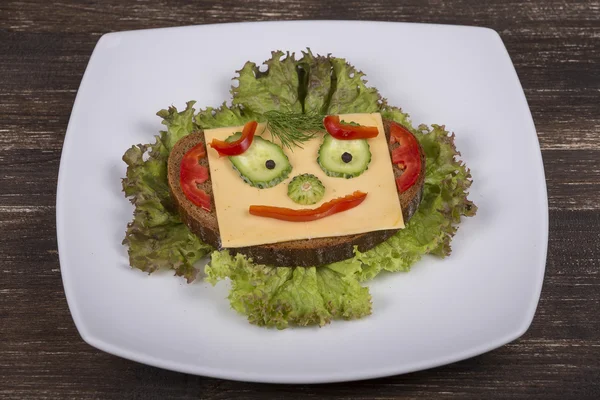 Gesicht auf Brot, aus Salat, Tomate, Gurke und Pfeffer. — Stockfoto