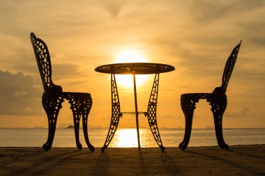 Table and two chairs at sunset clipart
