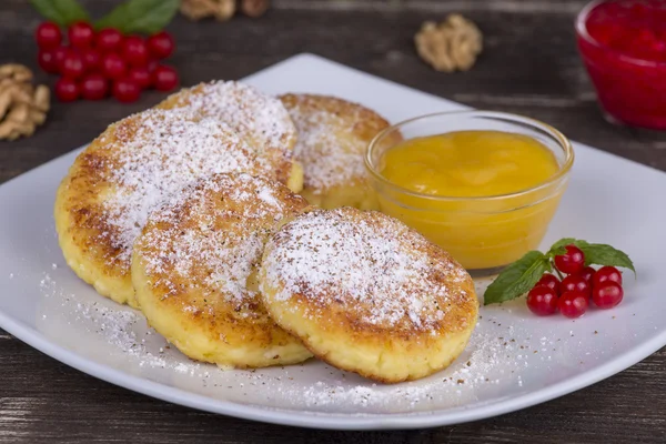Läcker hemlagad ost pannkakor med honung i vit platta — Stockfoto