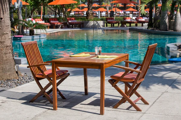 Table and chairs in empty cafe next to the swimming pool, Thailand — Stock Photo, Image